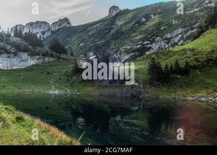 The mountain hut and the Alpstein mountain range reflecting on the Faelensee lake in the Swiss canton of Appenzell at sunrise Stock Photo