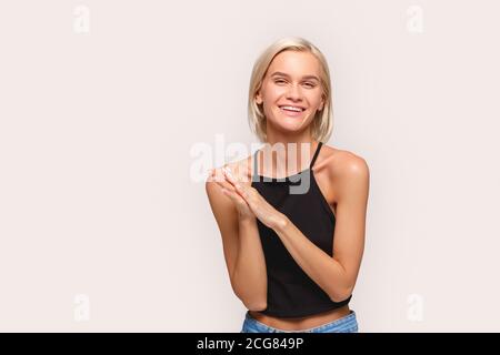 Freestyle. Young blonde woman in jeans and top standing isolated on white clapping laughing cheerful copy space Stock Photo