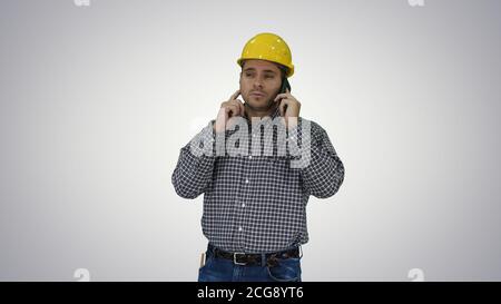Construction worker using smartphone on gradient background. Stock Photo
