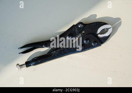 metal pipe clamped with Locking pliers also known as Vise-Grips or a Mole wrench or a vice grip . Close up macro Stock Photo