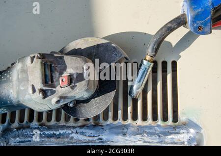 Sawing a weld seam on iron corners with an angle grinder with selective focus on flying sparks. The process of cleaning and grinding a metal corner Stock Photo