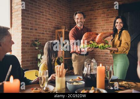 Portrait of nice attractive cheerful big full family meeting wife husband married couple carrying plate fresh homemade turkey serving table occasion Stock Photo
