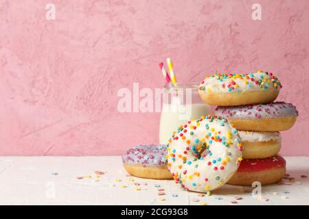 Milk and tasty donuts against pink background Stock Photo