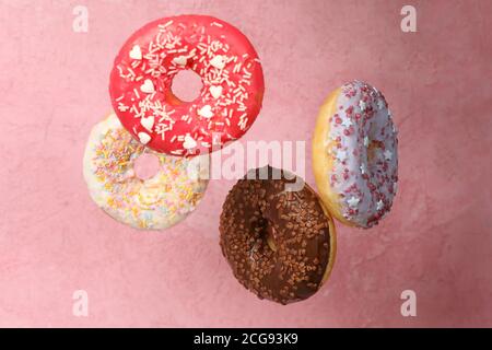 Four different tasty donuts on pink background Stock Photo