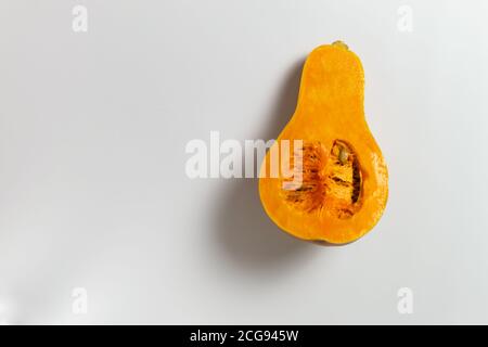 Sliced pumpkin with seeds and pulp on a white background. Copy space. Selective focus. Minimalism. Stock Photo