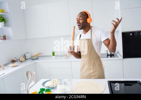 Portrait of his he nice attractive cheerful dreamy funky guy meloman making handmade pie cake using pin mic singing hit melody in modern light white Stock Photo