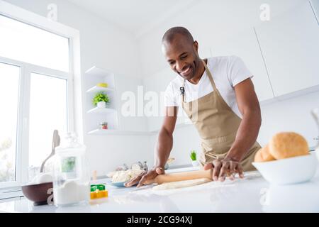 Portrait of his he nice attractive cheerful guy making handmade bread pizza pie cake rolling dough enjoying hobby free time in modern light white Stock Photo