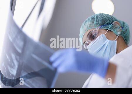 Doctor in protective medical mask looks at an X-ray. Stock Photo