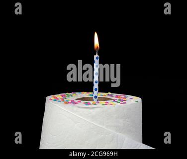 lit polka dot birthday candle in white toilet paper roll isolated on black Stock Photo