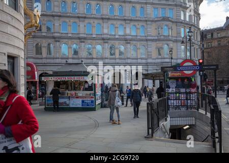 Entrance and exit seen from Charing Cross Underground station with people and tourist kiosks on the side of the road next to Trafalgar Square. Stock Photo