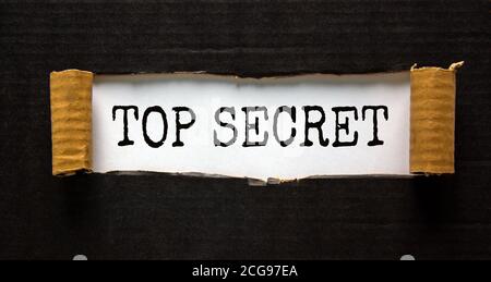 The word 'top secret' appearing behind torn black paper. Business concept. Stock Photo