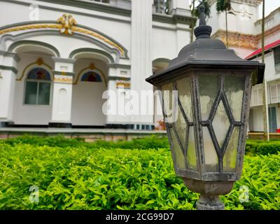 Old fashioned streetlamp beside a sidewalk with blurred buildings in background. Stock Photo