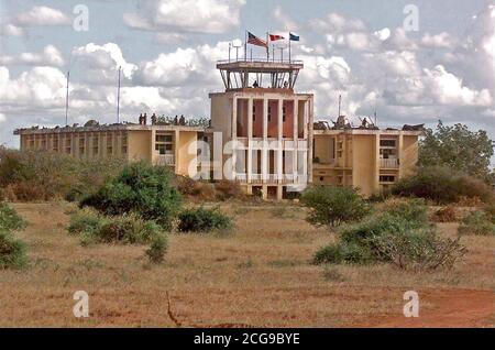 1992 - Soldiers from combined US and Canadian Forces secure an abandoned headquarters and control tower building at Baledogle, Somalia.  Members of the 10th Mountain Division, Fort Drum, New York and Air Force Combat Controllers are seen on the roof and in the control tower.  The flags of the United States, Canada and United Nations fly over the control tower.  This mission is in support of Operation Restore Hope.