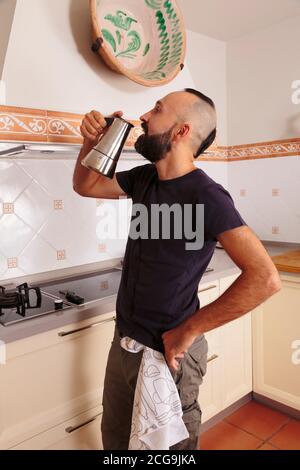 Young hispanic self-sufficient man drinking directly from the coffee pot Stock Photo