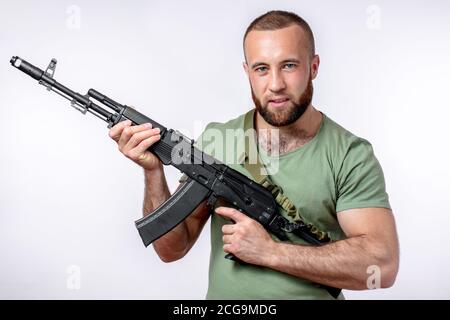 Bearded manful guy of european appearance in casual clothing looking at camera, holding sniper rifle in hands isolated on white Stock Photo