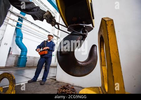 Workers using crane on titanium metallurgy plant. For loading titanium sponge to vacuum arc furnace. Stock Photo