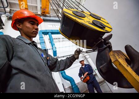 Workers using crane on titanium metallurgy plant. For loading titanium sponge to vacuum arc furnace. Stock Photo