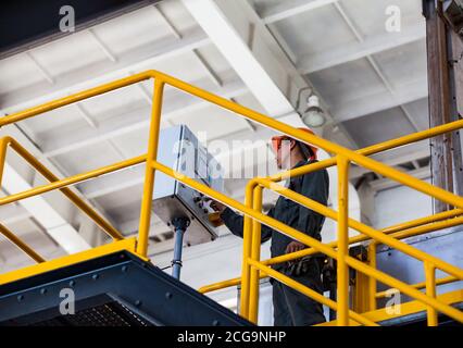 Worker controls the processing on pressing machine. Squeezing the titanium sponge on titanium metallurgy plant. Stock Photo
