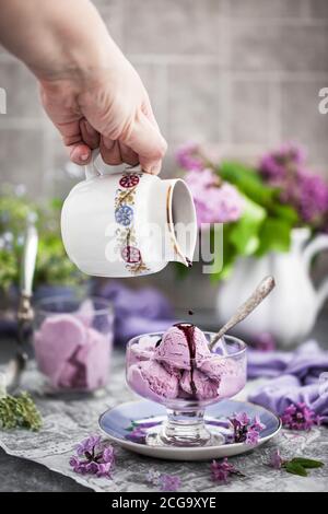Cup of delicious homemade blueberry ice cream and lilac on background Stock Photo