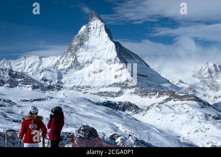 Zermatt, Switzerland - Feb 18 2020: Two young women on skis with a view on the Matterhorn in winter. Stock Photo