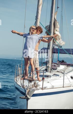People standing on bow of a sailing boat with hands aside like dramatic couple in Titanic movie. Loving man and romantic woman on yacht. Unforgettable Stock Photo
