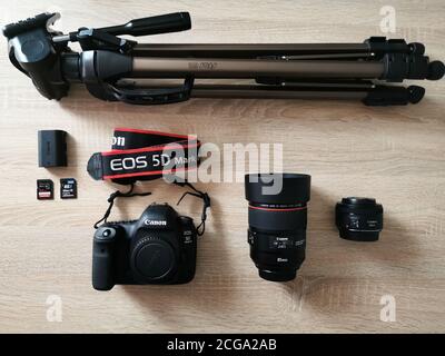 Set of the camera and photography equipment: two lens, body canon 5d mark iv, two memory card, battery and tripod on wood desk Stock Photo