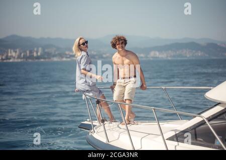 Caucasian couple standing on the front of a sail boat sailing on a calm blue sea. Beautiful seascape with copy space. Stock Photo