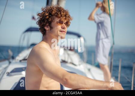 sailing, vacation, tourism, travel and people concept - young handsome man on sail boat or yacht floating in sea Stock Photo