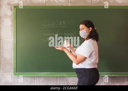 teacher with face mask explains how to use the antibacterial gel Stock Photo