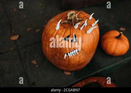 Close up of spooky carved pumpkin with teeth sitting on porch Stock Photo