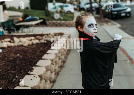 School aged boy dressed as Dracula Trick-or-Treating during Halloween Stock Photo