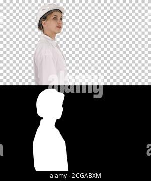 Young woman in hard hat walking and looking around, Alpha Channel Stock Photo