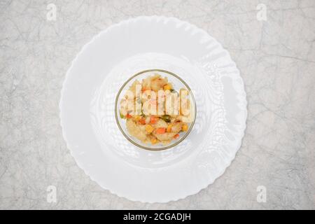 Close up of Vegetable macaroni cooked in White sauce served in a transparent bowl isolated on white background. Cooked pasta with carrot, corn, capsic Stock Photo
