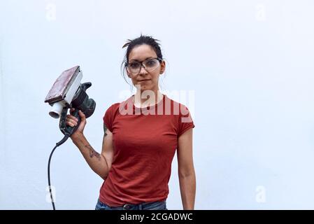 young woman with a power sander on a white background. Concept of manual work Stock Photo