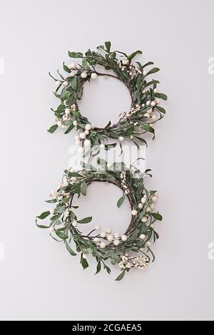 Two decorative mistletoe wreaths hanging on the white wall. Home decor in Celtic Christmas tradition Stock Photo