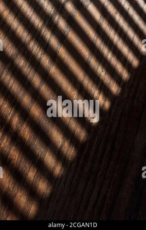 Shadows from Venetian blinds create lines on and old wooden coffee table Stock Photo