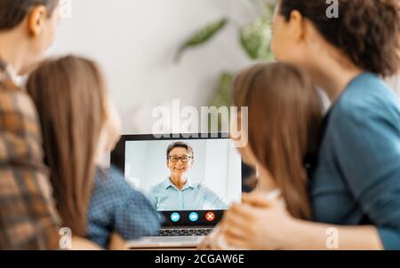 Happy loving family. Father, mother and daughters girls using laptop pc for remote conversation with grandma. Funny mom, dad and lovely children are h Stock Photo