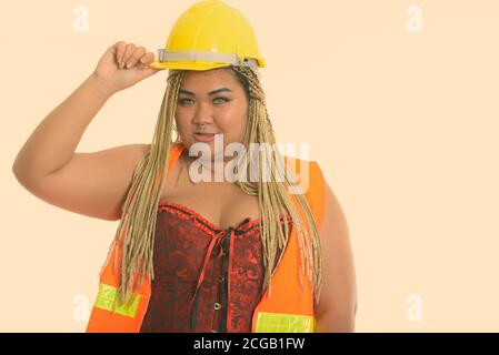 Young fat Asian construction woman holding safety helmet on head Stock Photo