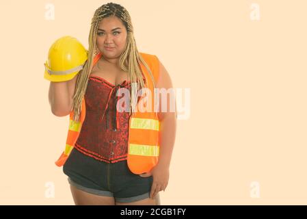 Young fat Asian construction woman holding and raising safety helmet Stock Photo