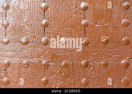 Old wooden wall with metal rivets painted orange. Stock Photo