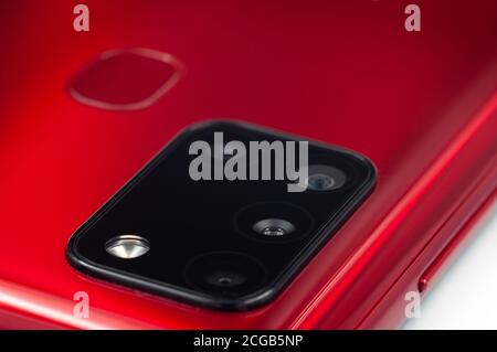 Red modern smart phone multi camera lens and fingerprint scanner close-up. Selective focus. Stock Photo