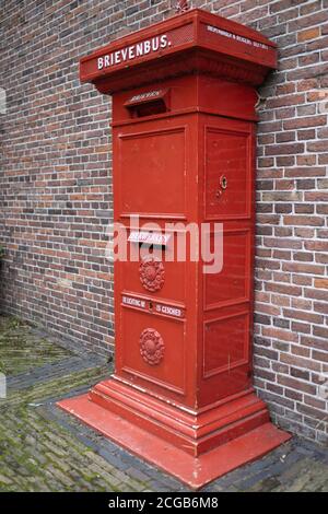 Traditional red metal post box set against a brick wall in Zaanse Schans, a typically small village in the Netherlands Stock Photo
