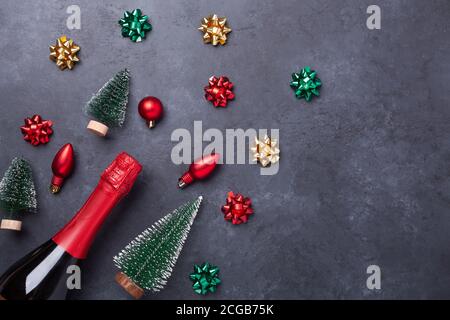Christmas composition with champagne and red, green, gold gifts and bows on dark stone background. Christmas and New Year holiday concept - Image Stock Photo