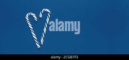Monochrome blue color Christmas composition. Two candy canes in shape of heart on wooden background. 2020 new year concept - Image Stock Photo