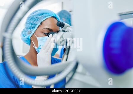Ophthalmologist looking through surgical microscope Stock Photo