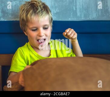 Portrait mischievous cute blond blue eyed boy making freckles face play laughing in happy mood. Funny photo, happiness lifestyle. Daycare, simple joys Stock Photo