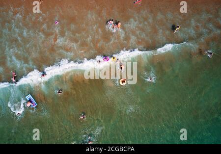 Aerial view of sandy beach with tourists swimming in beautiful clear sea water Stock Photo