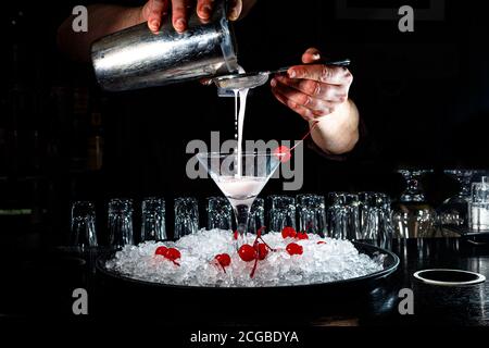 The bartender prepares a cocktail with yogur or milk on the counter of the dark bar. Stock Photo