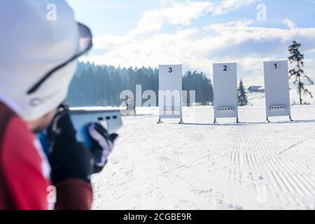 Leisure biathletes shooting with a laser rifle on a cold and sunny winter day Stock Photo