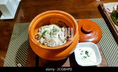 Stewed mushrooms with sour cream and potatoes in a pot is a traditional dish of Russian cuisine. Stock Photo